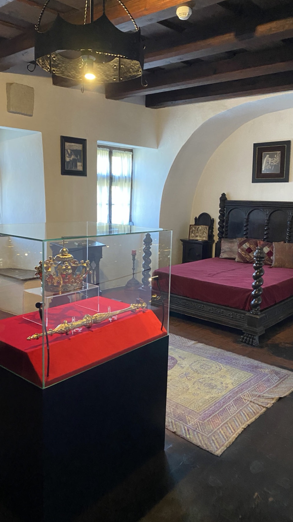 A castle bedroom with a crown and a sword displayed in a glass case