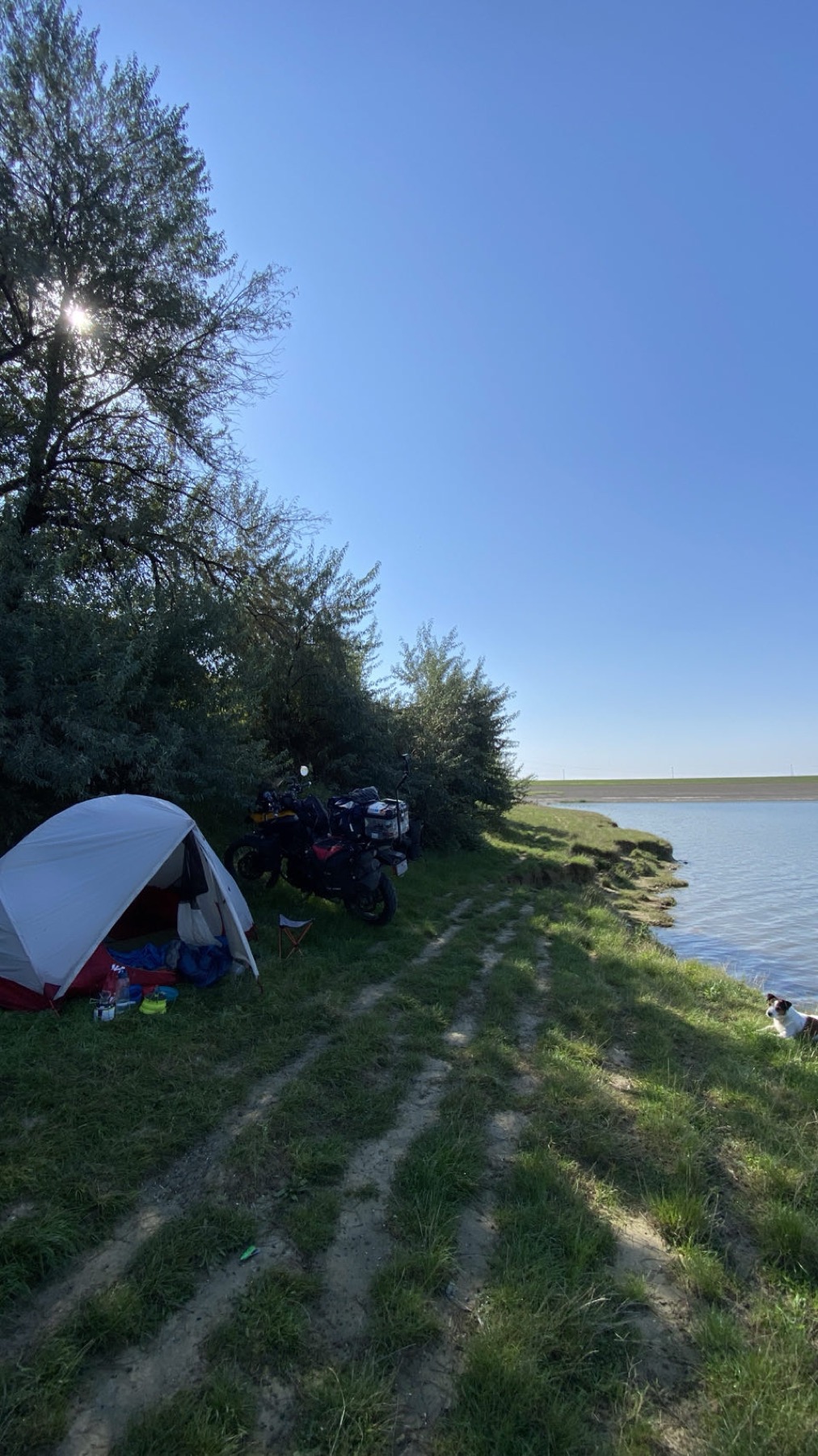 The tent pitched on the grass at the edge of the reservoir