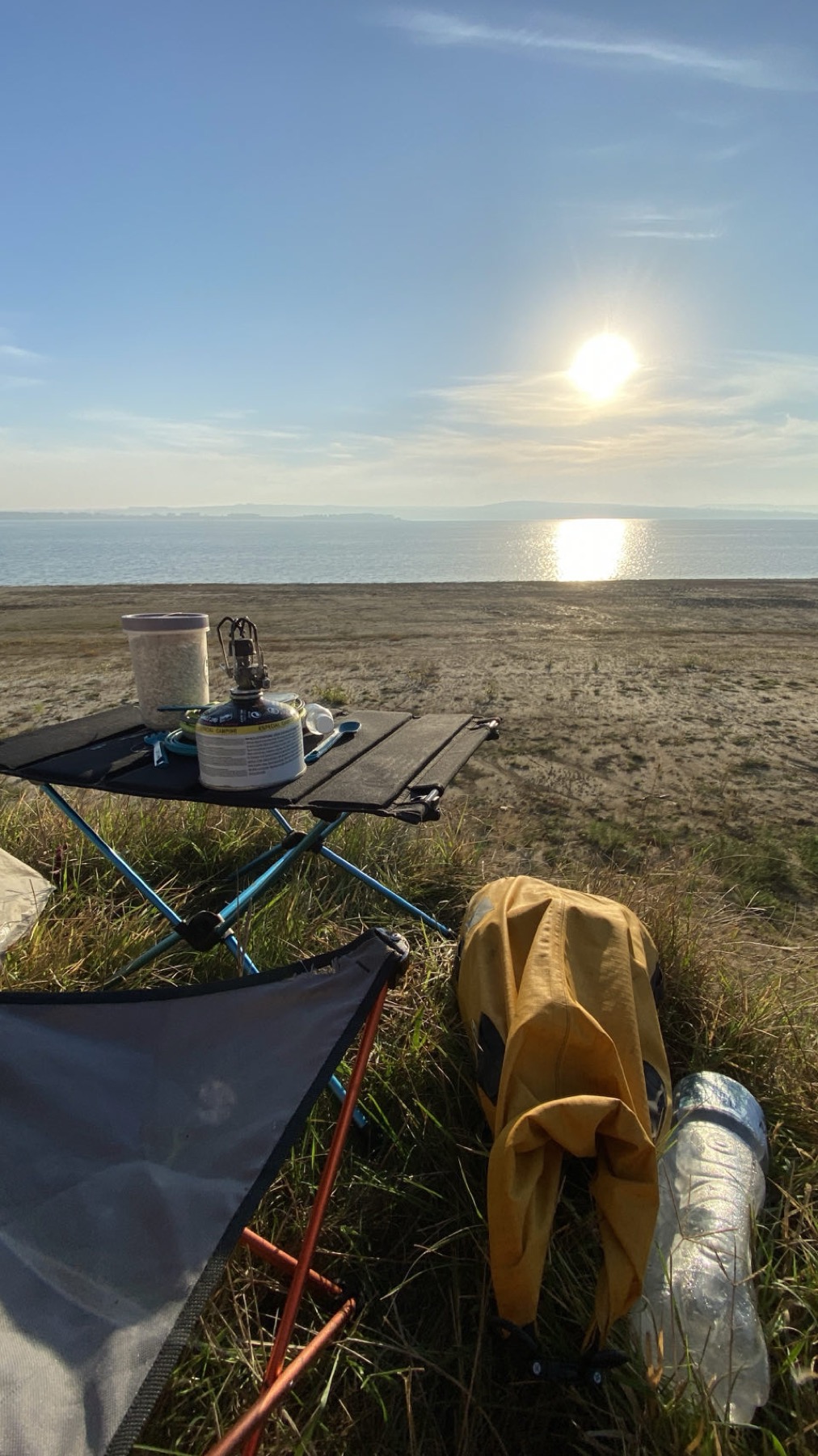 A camping stove on a small table above the water at dawn