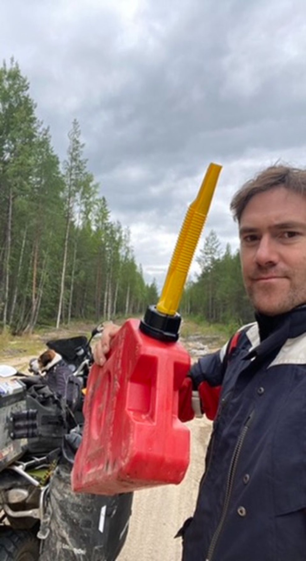 Rodrigo holding a spare fuel can beside the motorcycle