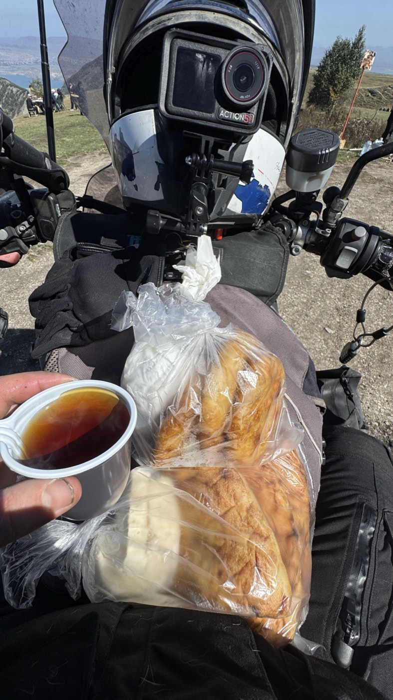 A cup of tea and a bag of pastries balanced on the motorcycle above the canyon