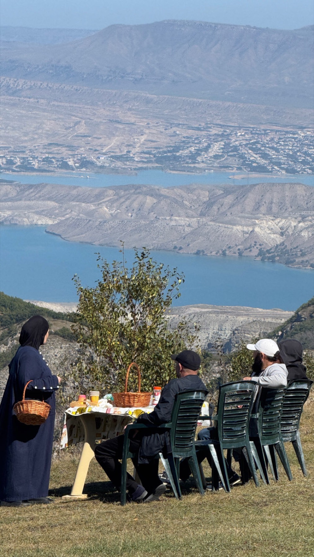 A family at a table on the grass above the canyon reservoir