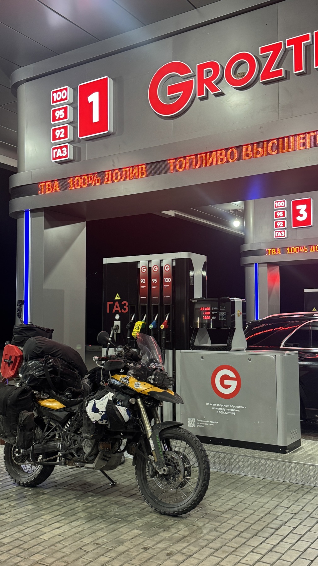 The motorcycle parked under the canopy of a petrol station in Chechnya at night