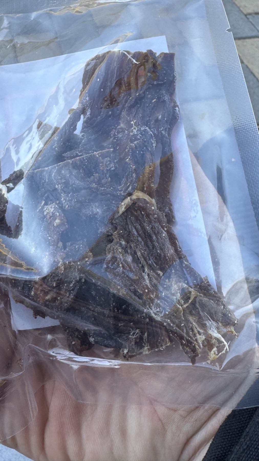 A bag of dried cured meat held in one hand