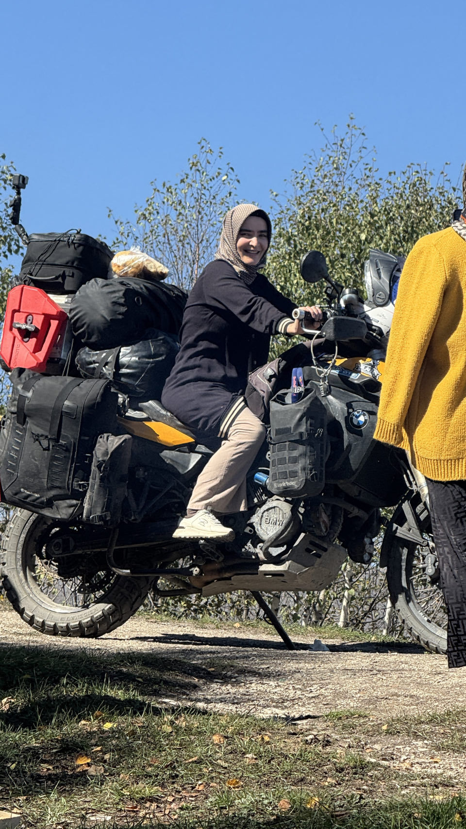 A woman in a headscarf sitting on the loaded motorcycle