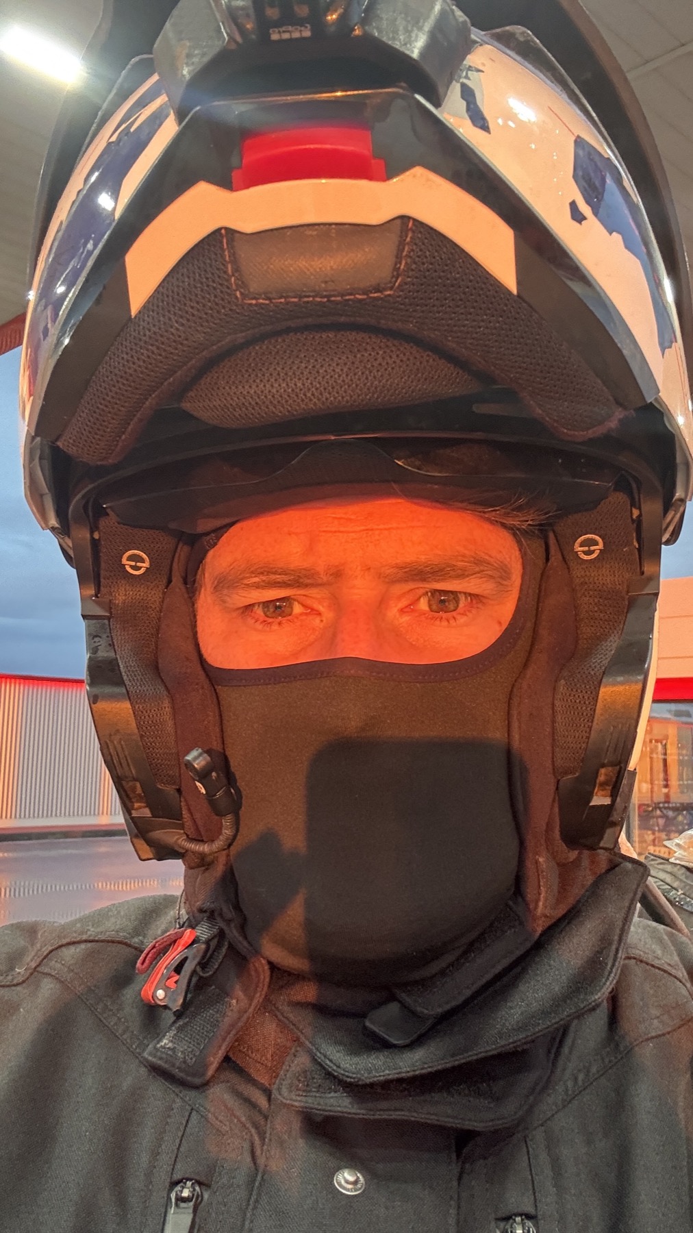 Close portrait of Rodrigo in helmet and balaclava, lit orange