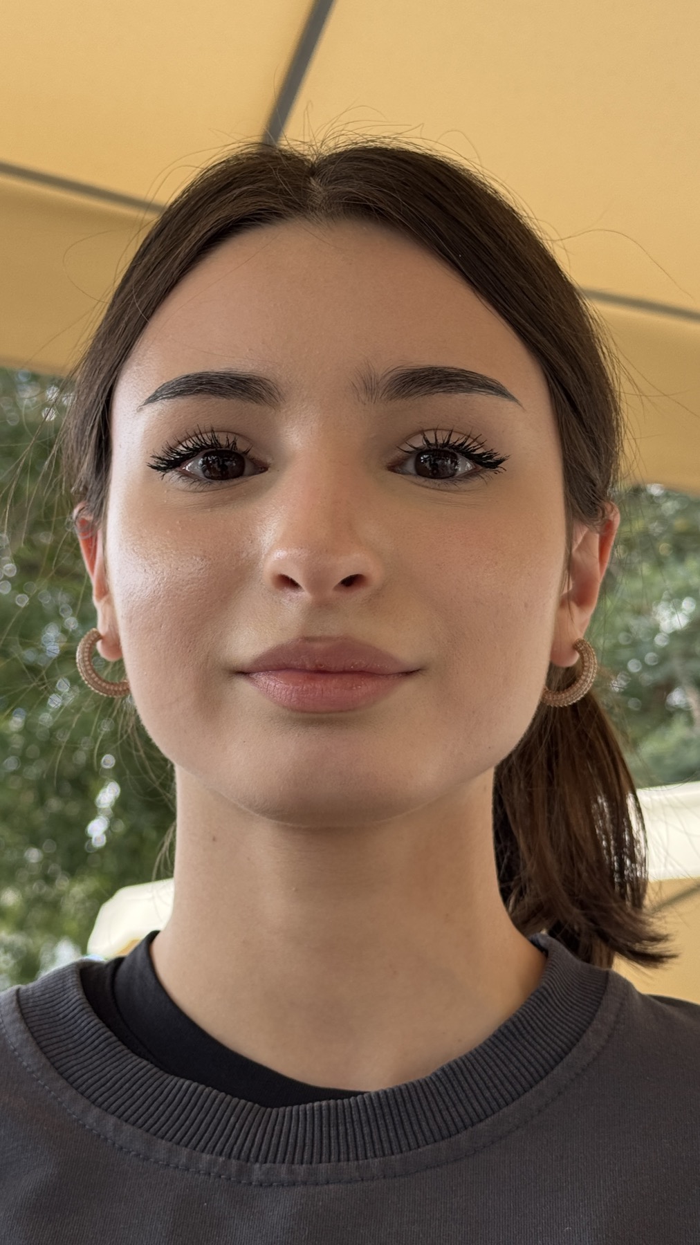 A young woman under a yellow awning on the cafe terrace
