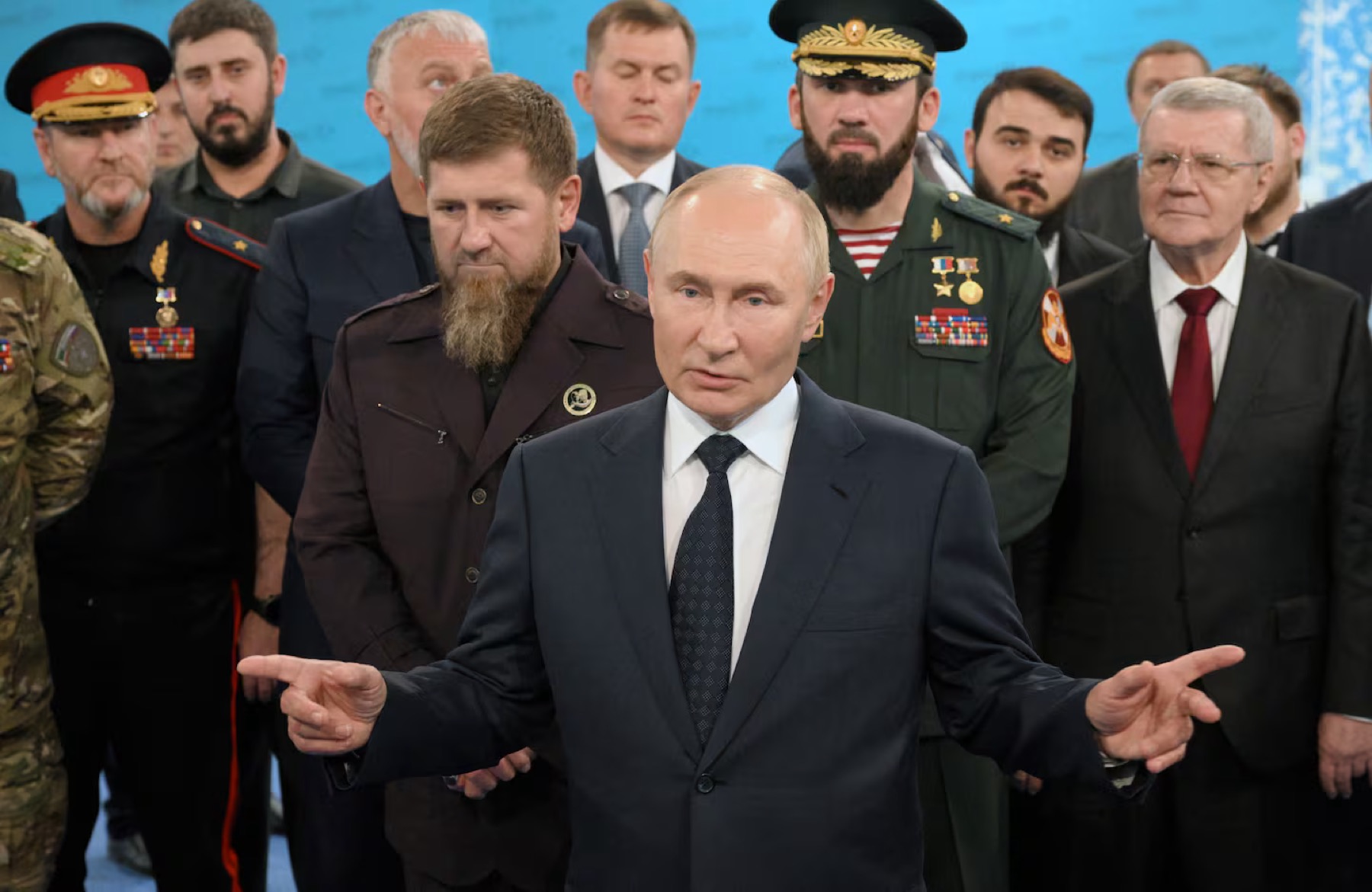 Ramzan Kadyrov standing behind Vladimir Putin among officials and officers