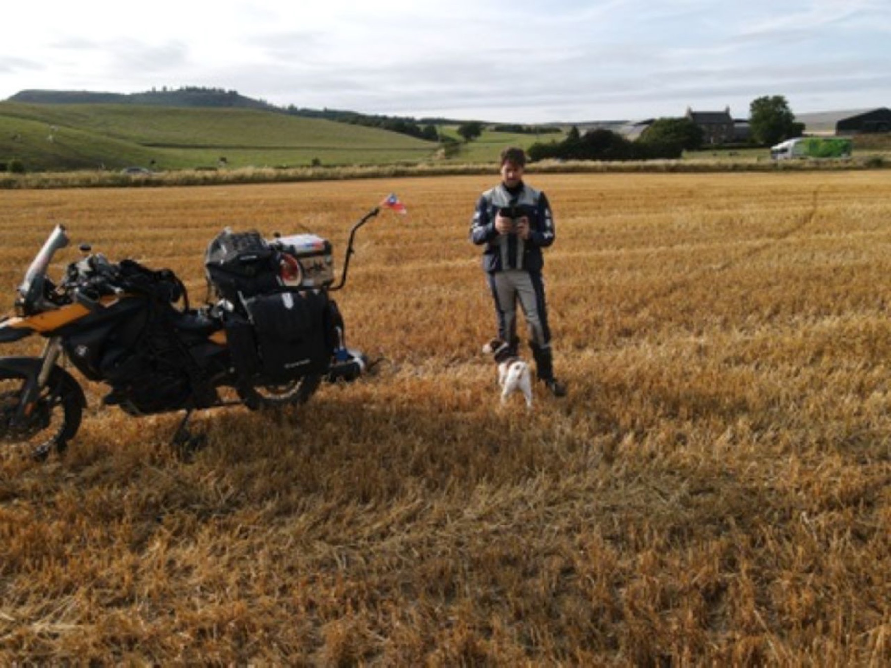 Rodrigo standing by the loaded bike in a field of cut wheat