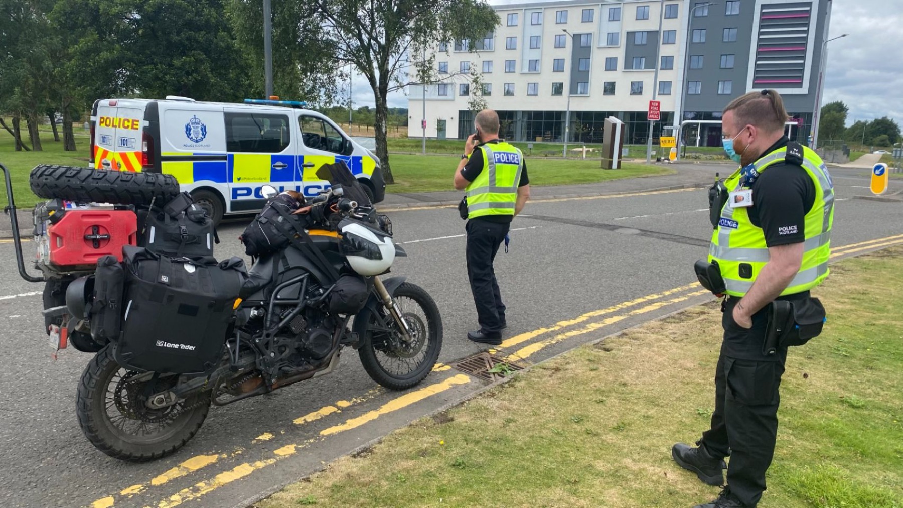 Police vehicles and officers around the loaded motorcycle in a city street