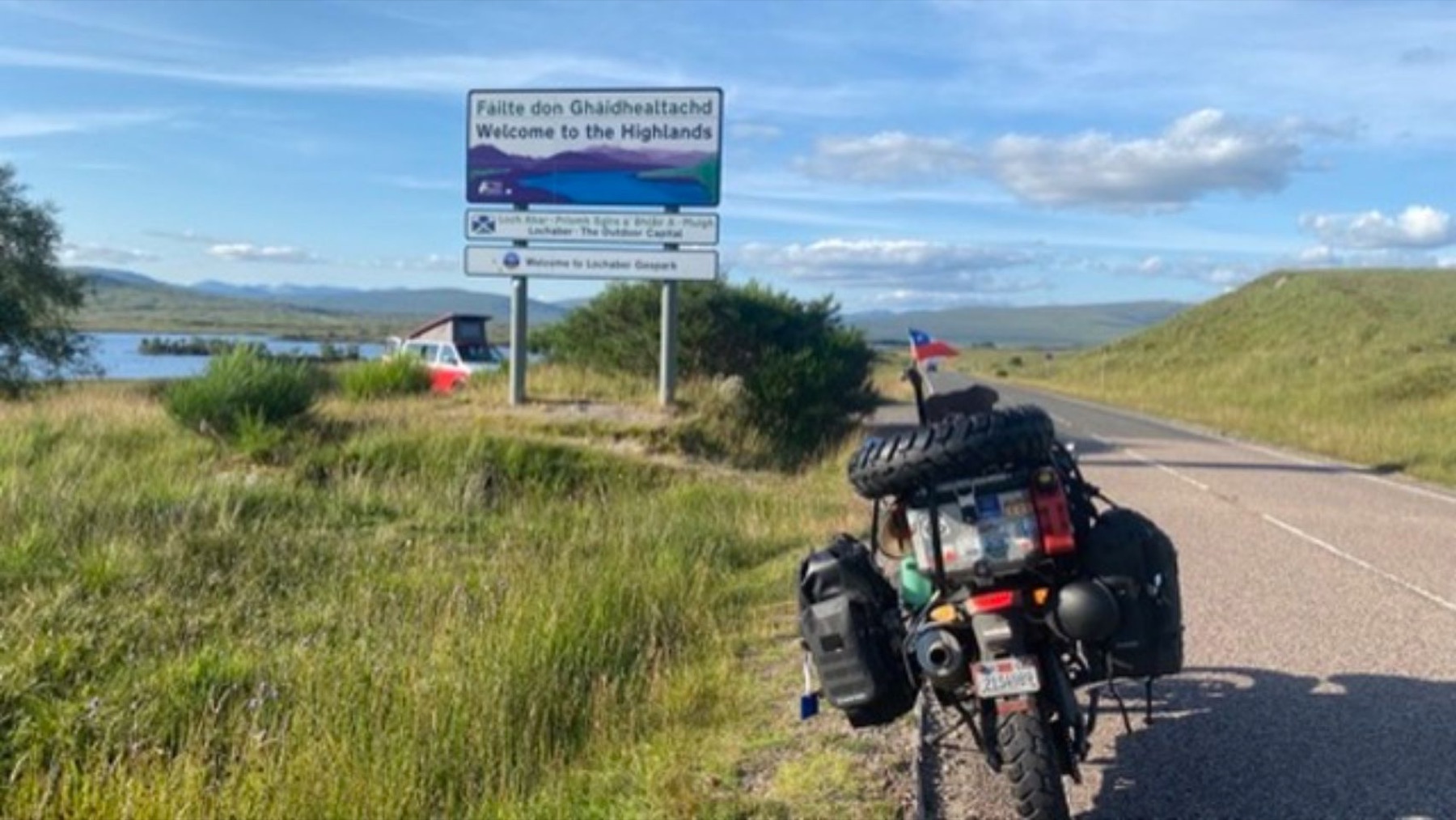 The bike beside a road sign reading Failte don Ghaidhealtachd, Welcome to the Highlands