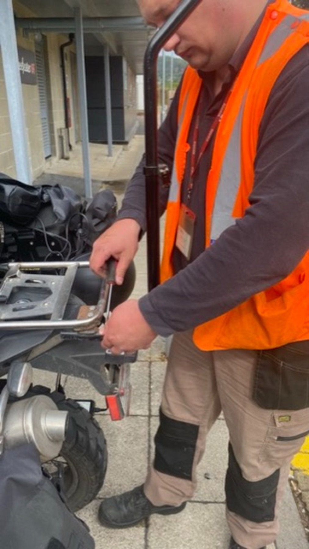 A man in a high visibility jacket working on the rear of the motorcycle