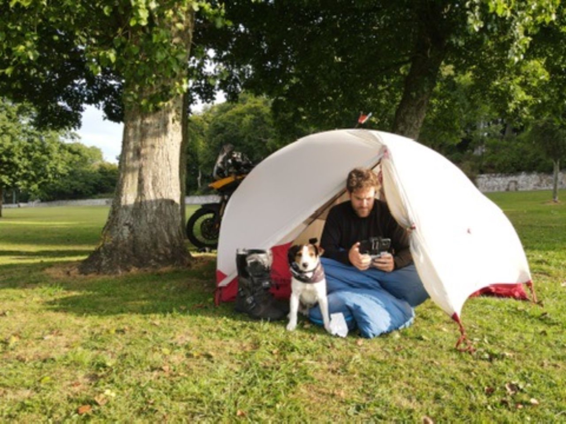 The tent under a tree with the bike parked beside it