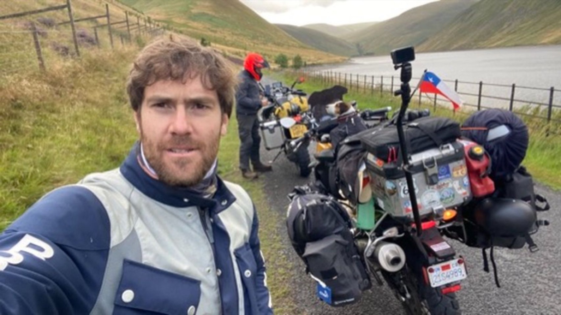 Rodrigo taking a selfie beside several loaded motorcycles on a Highland road
