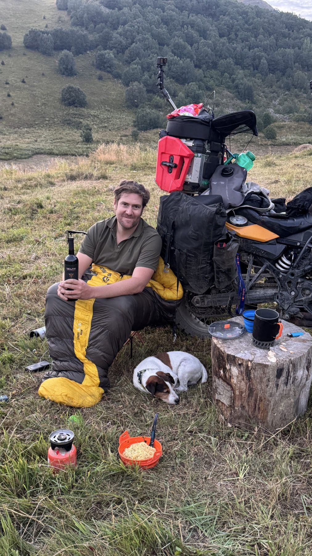 Rodrigo sitting beside the motorcycle with food and wine
