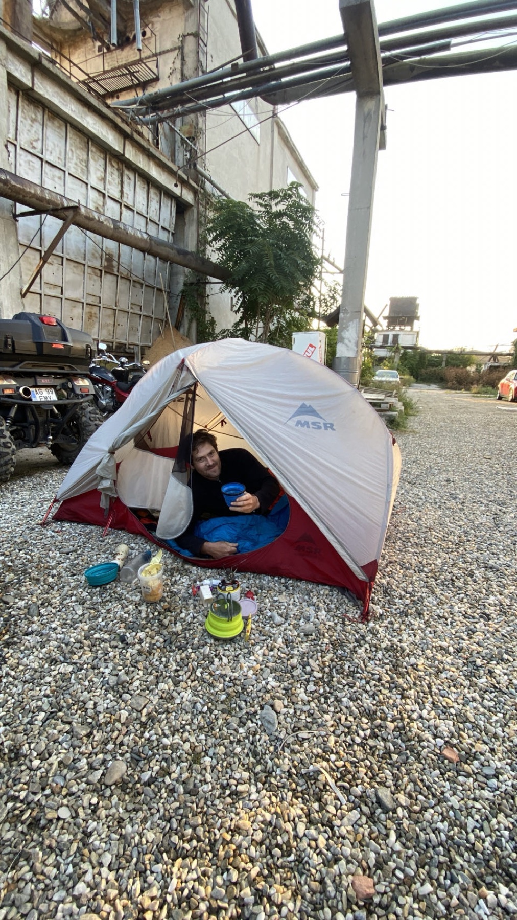 The tent pitched under a workshop roof beside the motorcycle