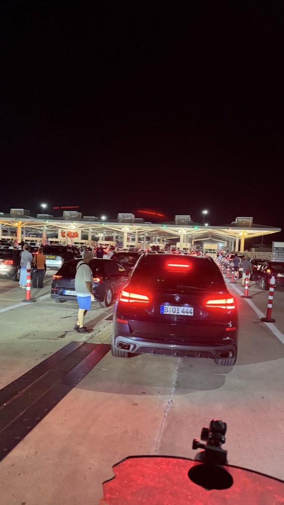 A queue of cars at a lit border post at night