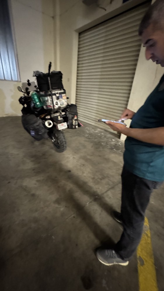 An official checking paperwork beside the loaded motorcycle inside a customs hangar