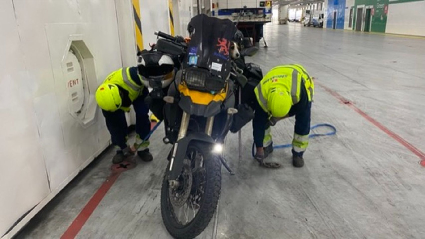 Port staff in high visibility jackets working around the loaded motorcycle